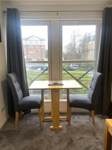 una mesa y dos sillas frente a una ventana en East Coast City Centre Dunfermline Apartment, en Fife
