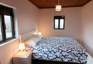 a bedroom with a blue and white bed and two windows at Casa da Laurinha in Arcos de Valdevez
