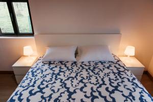 a bedroom with a bed with two pillows and two lamps at Casa da Laurinha in Arcos de Valdevez