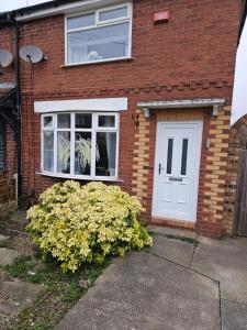 a brick house with a white door and a bush at Beautiful Home from Home in Manchester in Manchester