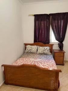 1 dormitorio con cama de madera y ventana en appartements meublée nr 1 en rez-de-chaussée, en Oujda
