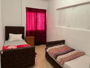 a bedroom with a bed and a window with red curtains at appartements meublée nr 1 en rez-de-chaussée in Oujda