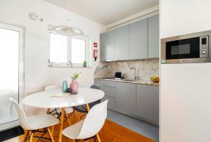 een witte keuken met een witte tafel en stoelen bij LAZ apartment in Porto