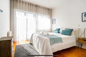 een witte slaapkamer met een groot bed en een raam bij LAZ apartment in Porto