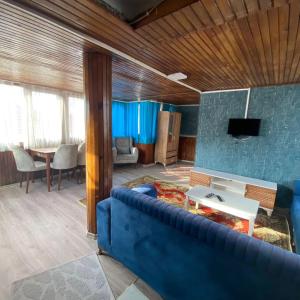 ein Wohnzimmer mit einem blauen Sofa und einem TV in der Unterkunft Smirnapalasapartotel in Konak