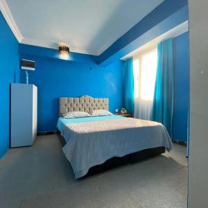 ein blaues Schlafzimmer mit einem Bett und einem Fenster in der Unterkunft Smirnapalasapartotel in Konak