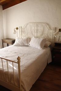 Cama blanca con sábanas y almohadas blancas en La Cija Olmedo, en Olmedo