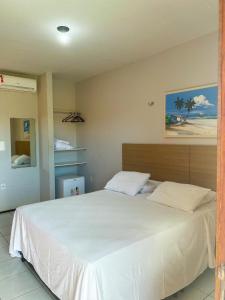 a bedroom with a large bed with white sheets at Pousada Missare in Canoa Quebrada