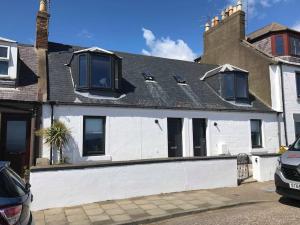 una casa blanca con techo negro en Creel Cottage (No.3), en Arbroath