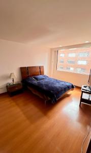 um quarto com uma cama com um cobertor azul num piso de madeira em Apto amplio en chico - calle 100 em Bogotá