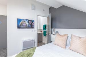 a bedroom with a white bed with a tv on the wall at Kilwick Lodge, Hartlepool City Centre, Room Stay in Hartlepool