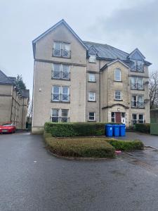 een groot gebouw met blauwe vuilnisbakken ervoor bij East Coast City Centre Dunfermline Apartment in Fife