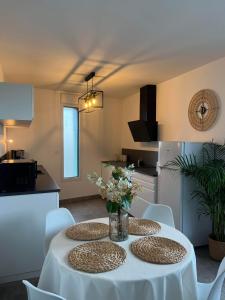 Les Terrasses de Saint Martin في رين: مطبخ مع طاولة وكراسي بيضاء في الغرفة