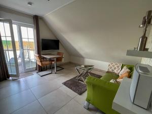 a living room with a green couch and a television at Huus am Meer in Norddeich