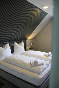 1 dormitorio con 2 camas con sábanas y almohadas blancas en Huus am Meer en Norddeich