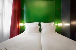 2 łóżka w pokoju z zieloną ścianą w obiekcie Soho Athinas 60 w Atenach