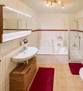 y baño con lavabo, bañera y ducha. en EulenNest Spacious Cozy Home with Private Garden en Lindenberg im Allgäu