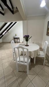a white table with white chairs and a vase of flowers at Apartamento Maracuyá en Tarija in Tarija