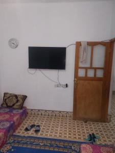 a bedroom with a tv on the wall and a door at Dar Dyafa in Er Rachidia