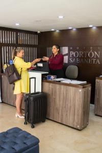 two women standing at a reception counter at an airport at Hotel Portón Sabaneta in Sabaneta