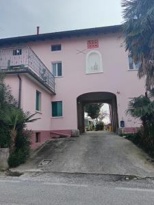 un gran edificio rosa con un túnel dentro en B&b Relax / Olga&Claudio, en Cassacco