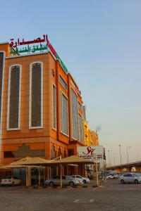 SADARA HOTELS APARTMENTS في صحار: مبنى فيه سيارات متوقفة في موقف للسيارات