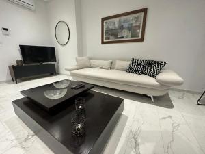 een woonkamer met een witte bank en een tafel bij Luxury appartement in La Marsa
