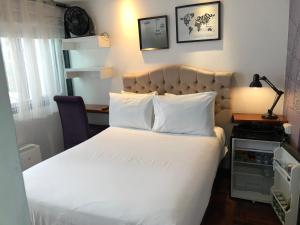 1 dormitorio con 1 cama grande con colcha blanca en La Casa del Viajero, en Lima