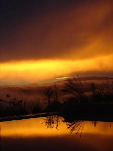 una puesta de sol sobre un cuerpo de agua con el cielo en Cabaña Vistas Paraíso, en La Suiza