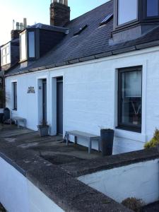 a white building with a bench in front of it at Creel Cottage (No. 4) in Arbroath