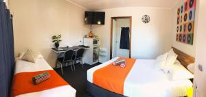 two beds in a room with a kitchen and a desk at Acacia Motel in Chinchilla