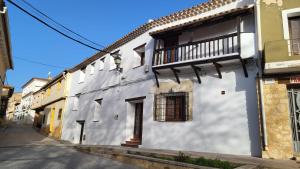 a white building with a balcony on a street at La Casona de Roser in Cardenete
