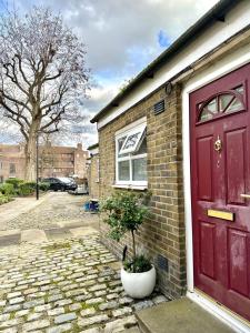 a red door of a brick house with a potted plant at Whites Inn in London