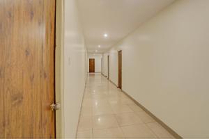 einen leeren Flur mit weißen Wänden und einer Holztür in der Unterkunft Hotel Ramoji in Surūrnagar