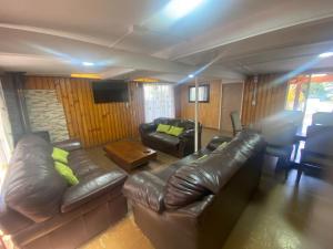 a living room with a leather couch and a table at Cabaña para 12 personas a una cuadra de playa chica in Licán Ray