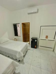 Serra de São Bento的住宿－Pousada Bouganville da Serra，一间白色卧室,配有两张床和垃圾桶