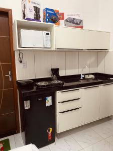 a small kitchen with a stove and a microwave at Pousada Bouganville da Serra in Serra de São Bento
