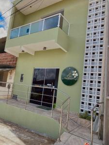 a green building with a balcony on the side of it at Pousada Bouganville da Serra in Serra de São Bento