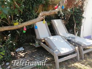 2 chaises longues assises sur une terrasse sous un arbre dans l'établissement Logement+parking proche métro - total autonome, à Villejuif