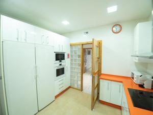 a kitchen with white cabinets and a clock on the wall at Apto Valdespino Gran Terraza fjHomefj in Jerez de la Frontera