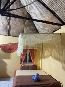 a bed in a room with a roof at Thuy - Gunter Garden Bungalow in Mui Ne