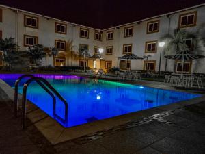 a swimming pool in front of a building at night at Hotel Kariña Guanipa in San José de Guanipa