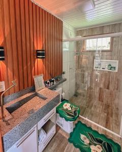 La salle de bains est pourvue d'une douche et d'un lavabo. dans l'établissement Chalés Florescer nos Canyons, à Praia Grande