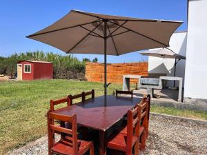 a wooden table with an umbrella and chairs at Casa de Campo en Cañete in Imperial