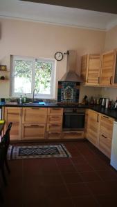 a kitchen with wooden cabinets and a sink and two windows at Villa with a big garden in Athens