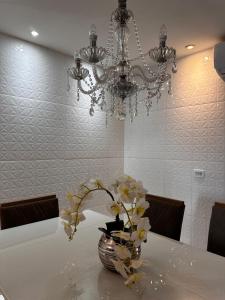 a vase with flowers on a table under a chandelier at Casa Parque nacional Serra da capivara in Coronel José Diaz