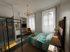een slaapkamer met een bed en een kroonluchter bij Maison à la Guitarde - Hôtel Particulier Hippolyte in Châteauroux