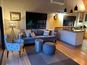 a living room with a couch and a kitchen at Whisper Cottage in Onetangi