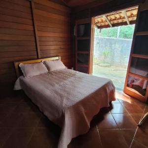 a bed in a room with a large window at Chácara Flores de Maio in Atibaia