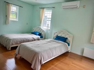 Villa美瑛・やさしい窓 في بيي: سريرين في غرفة بجدران زرقاء